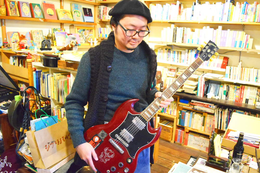 愛用のギターを持つ山田さん