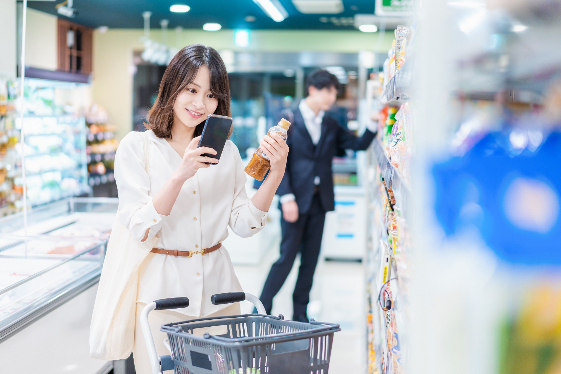 スマートフォンを見ながら買い物をする女性